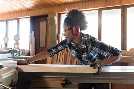 Woman wearing hearing protection while doing woodworking. 