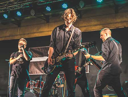 3 Musicians on stage that need hearing protection.